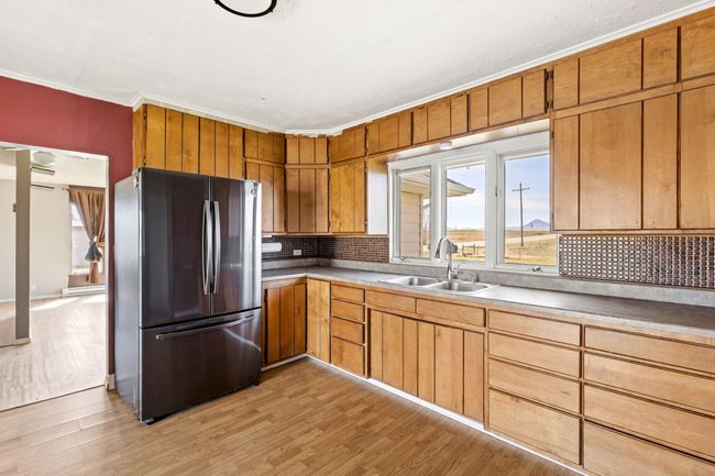 Kitchen with freestanding refrigerator, ornamental molding, backsplash, light wood finished floors, and a sink | Image 21