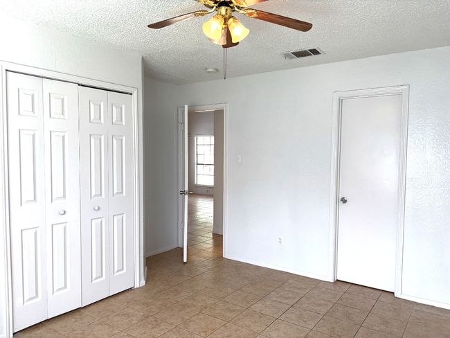 Unfurnished bedroom featuring a textured ceiling, light tile patterned flooring, a closet, and ceiling fan | Image 9