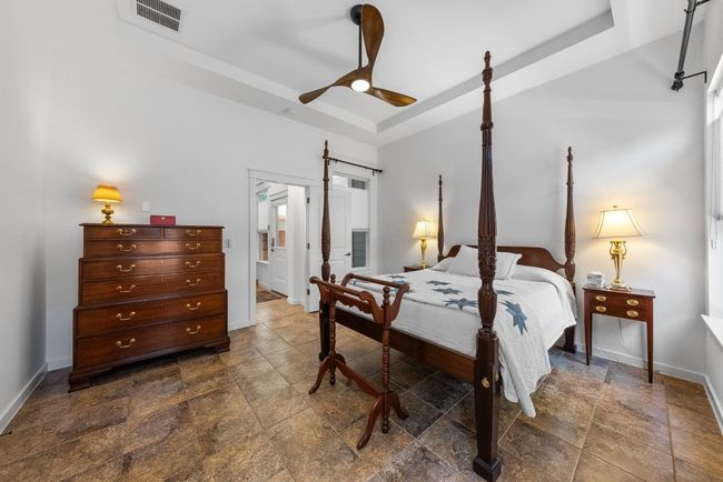 Bedroom featuring baseboards, a ceiling fan, a barn door, visible vents, and a raised ceiling | Image 17