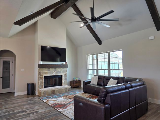 Living room with beam ceiling, dark wood finished floors, high vaulted ceiling, a fireplace, and arched walkways | Image 6