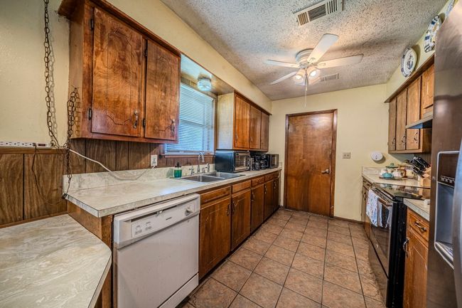 Kitchen with white dishwasher, range with electric stovetop, a ceiling fan, light countertops, and a textured ceiling | Image 12