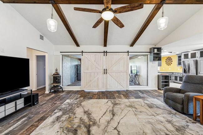 Overall, the combination of high wood-beamed ceilings, double barn doors, wood-like tile flooring, and a light color palette makes the main living area a stunning centerpiece of the home—a perfect space for relaxing, entertaining, and enjoying time with family and friends | Image 21