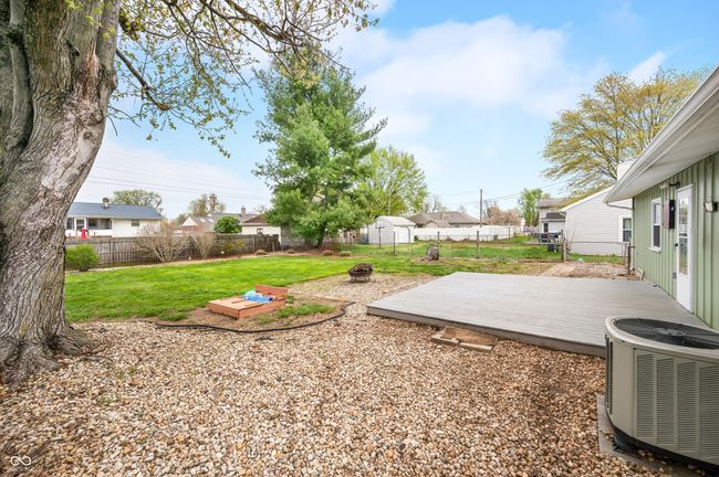 view of yard featuring a wooden deck, a fenced backyard, an outdoor fire pit, and central AC unit | Image 10