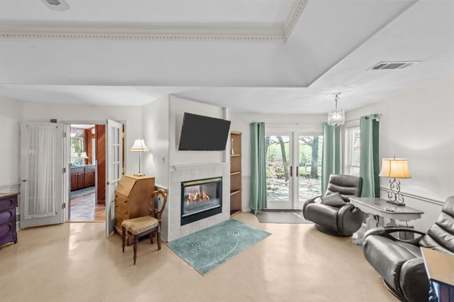 Living area with a tray ceiling, visible vents, and a tile fireplace | Image 13
