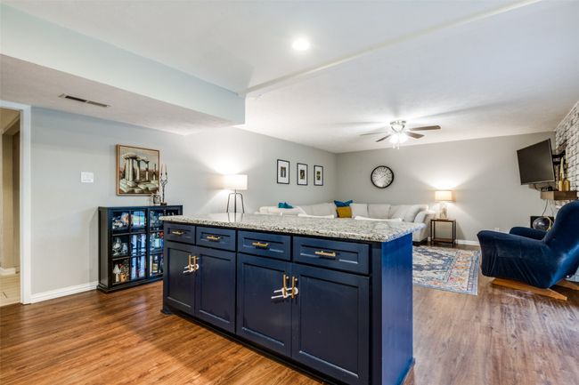 Kitchen featuring open floor plan, large island, ceiling fan, blue cabinetry, and dark wood-style flooring | Image 9