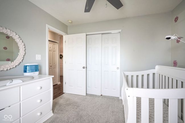 bedroom featuring a ceiling fan, a nursery area, light carpet, and a closet | Image 24
