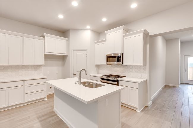 Kitchen with appliances with stainless steel finishes, a sink, backsplash, light wood-style flooring, and recessed lighting | Image 11