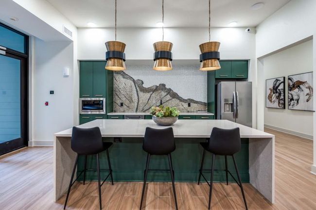 Kitchen featuring light hardwood / wood-style floors, stainless steel appliances, a breakfast bar, and a center island | Image 36