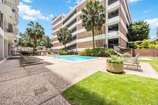 Spacious outdoor pool area with lounge chairs, surrounded by palm trees and well-maintained landscaping, offering a relaxing and inviting atmosphere. | Image 29