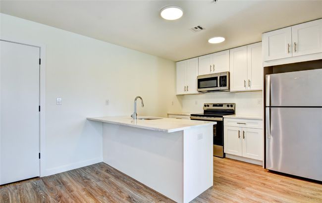 Kitchen with a sink, visible vents, light wood-type flooring, and appliances with stainless steel finishes | Image 32