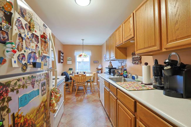 Kitchen featuring white appliances, light countertops, a sink, washer / dryer, and decorative light fixtures | Image 6