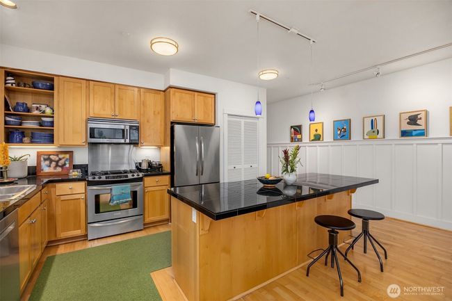 The kitchen is graced with stainless steel appliances, maple cabinets and a breakfast counter. | Image 9