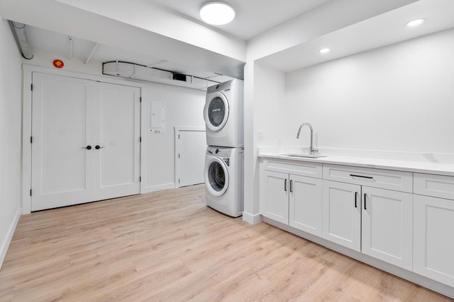 Clothes washing area with stacked washer and dryer, recessed lighting, light wood-type flooring, and a sink | Image 17