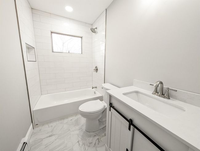 Full bath featuring shower / bath combination, toilet, marble finish floor, baseboard heating, and vanity | Image 15