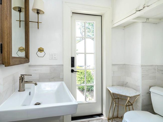Bathroom featuring a sink, tile walls, toilet, and wainscoting | Image 13