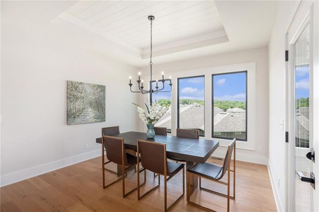 Dining area with a raised ceiling, a chandelier, plenty of natural light, light wood finished floors, and ornamental molding | Image 14