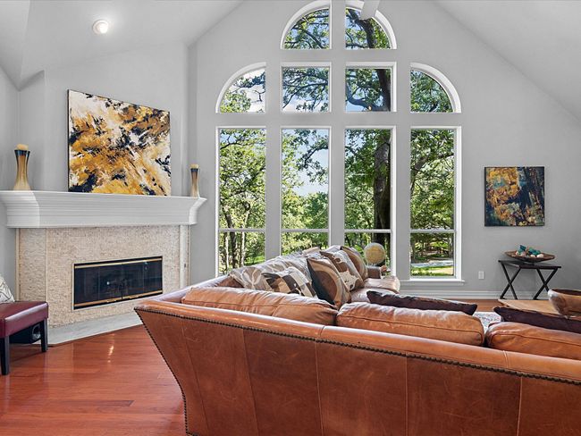 Living room featuring wood finished floors, healthy amount of natural light, high vaulted ceiling, and a fireplace. Floor to ceiling windows facing north. | Image 7