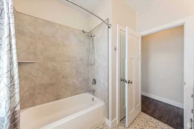 Bathroom featuring shower / tub combo, baseboards, and wood finished floors | Image 34
