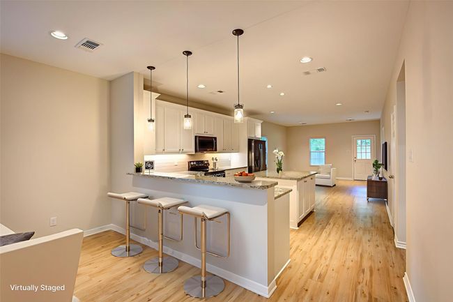 Kitchen with stainless steel appliances, light wood-style flooring, a peninsula, white cabinets, and tasteful backsplash | Image 7