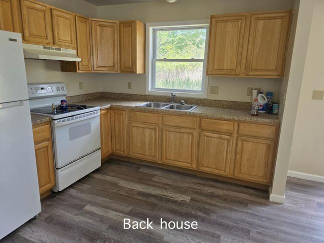 Kitchen featuring white appliances, under cabinet range hood, and dark wood-style floors | Image 10
