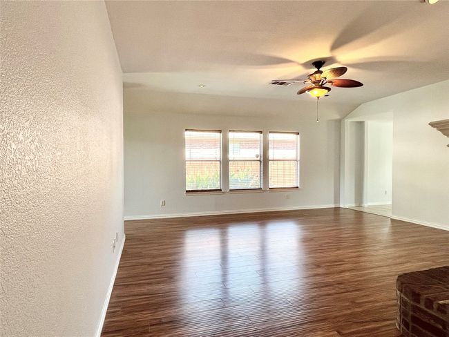 Unfurnished living room featuring dark wood finished floors, a ceiling fan, and a textured wall | Image 11