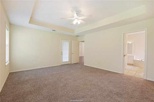 Spare room featuring light colored carpet, a tray ceiling, crown molding, a ceiling fan, and baseboards | Image 15