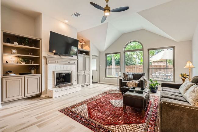 Living room with a ceiling fan, light wood-style flooring, a brick fireplace, and lofted ceiling | Image 4