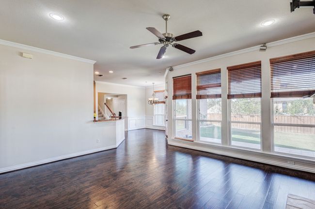 Empty room with ornamental molding, ceiling fan with notable chandelier, and dark hardwood / wood-style floors | Image 18