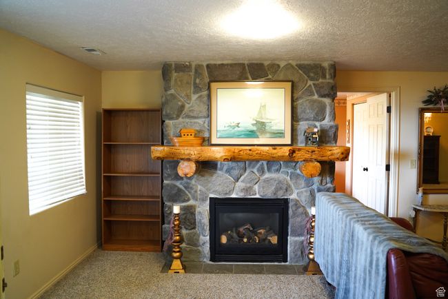 Living area featuring a fireplace, a textured ceiling, and carpet flooring | Image 20