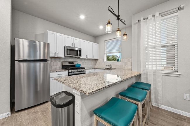 The kitchen is a modern masterpiece, featuring quartz countertops, stainless appliances, and shaker style cabinetry, perfect for those who love to cook in style | Image 11