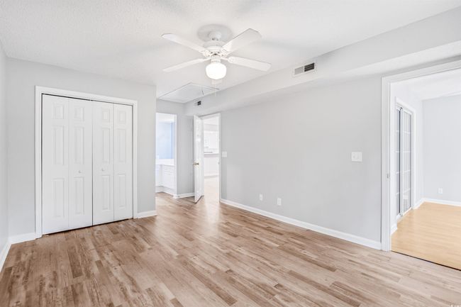 Unfurnished bedroom with light wood-style flooring, attic access, a closet, and ceiling fan | Image 23