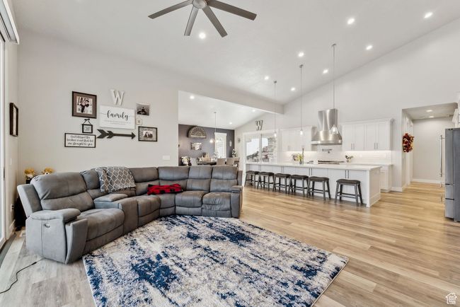 Living area featuring light wood-style floors, a ceiling fan, high vaulted ceiling, and recessed lighting | Image 48