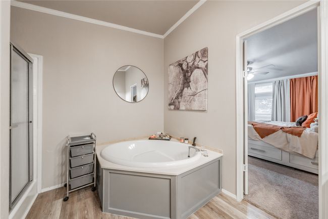 Ensuite bathroom featuring a garden tub, wood finished floors, crown molding, and a ceiling fan | Image 22
