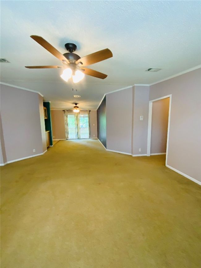 Empty room featuring visible vents, crown molding, baseboards, light colored carpet, and ceiling fan | Image 15