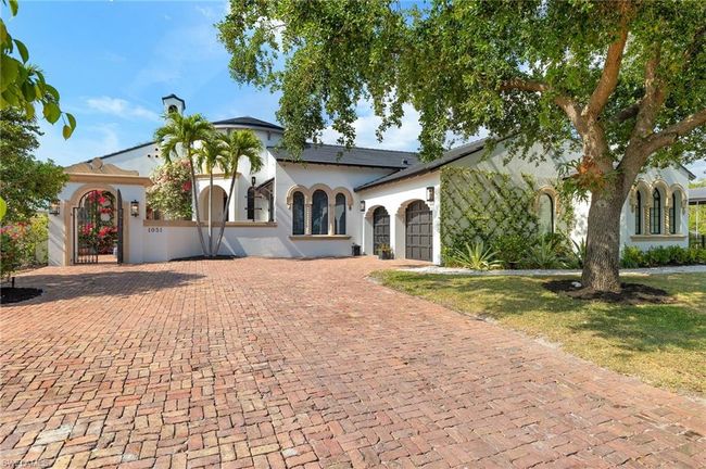 Mediterranean / spanish home featuring a chimney, a gate, decorative driveway, an attached garage, and stucco siding | Image 5