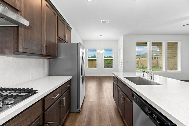 Kitchen with a sink, appliances with stainless steel finishes, range hood, dark wood-style floors, and a chandelier | Image 15