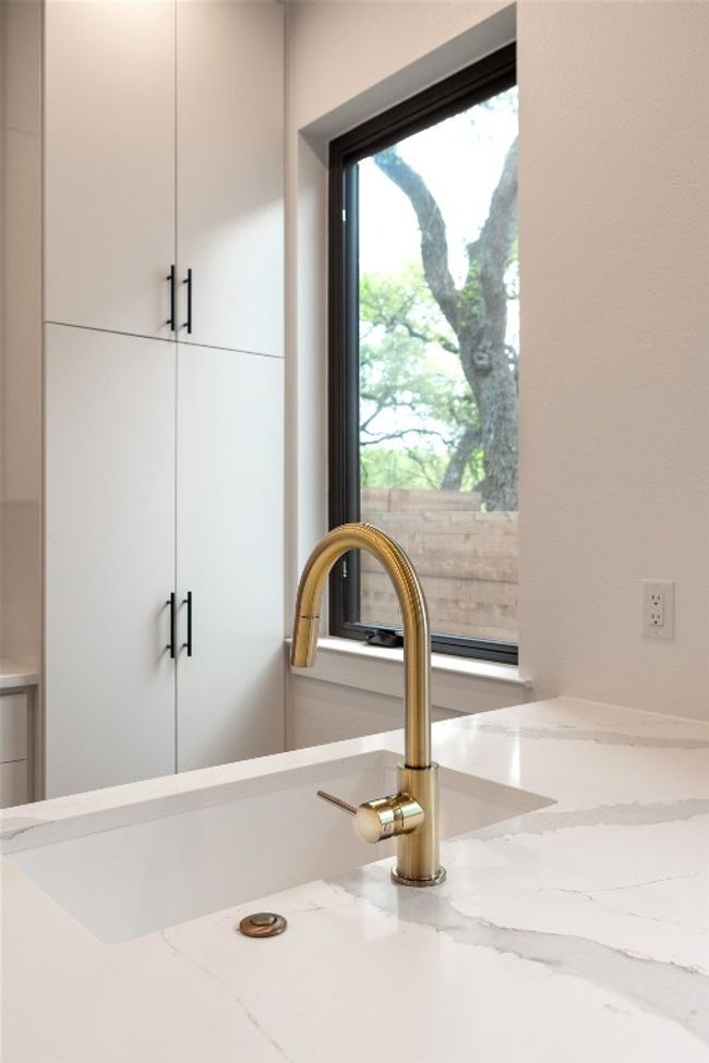 Kitchen view of light stone counters, white cabinets, and modern cabinets | Image 14