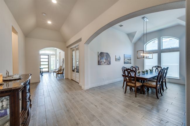 Dining room featuring lofted ceiling, arched walkways, light wood-style floors, a chandelier, and baseboards | Image 6
