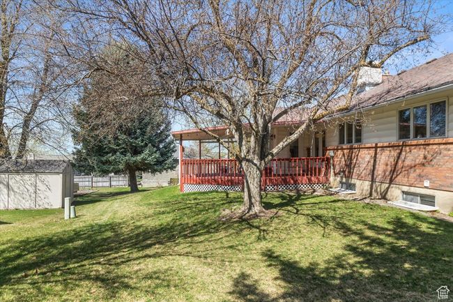 View of yard featuring a wooden deck, fence, a storage unit, and an outdoor structure | Image 39