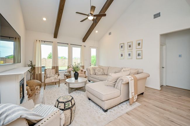 Inviting living room features exposed ceiling beams and a cozy fireplace, creating a warm and welcoming atmosphere | Image 8
