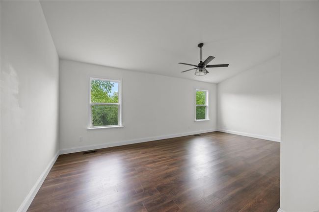 Unfurnished room with dark wood-style flooring, ceiling fan, baseboards, lofted ceiling, and visible vents | Image 36