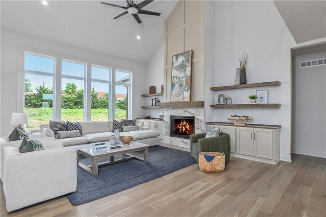 Living room with light hardwood / wood-style flooring, a premium fireplace, ceiling fan, and high vaulted ceiling | Image 8