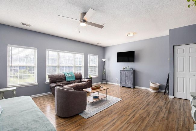 Living room with ceiling fan, plenty of natural light, wood finished floors, a textured ceiling, and baseboards | Image 7