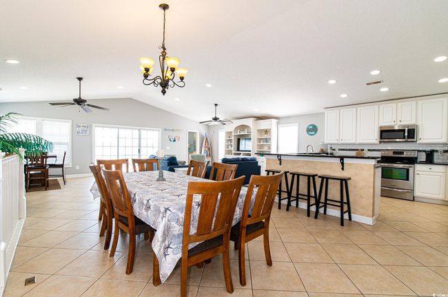 Dining area featuring ceiling fan, lofted ceiling, light tile patterned floors, a chandelier, and recessed lighting | Image 19