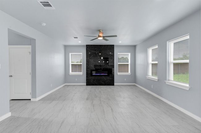 Unfurnished living room with healthy amount of natural light, ceiling fan, a premium fireplace, and recessed lighting | Image 7