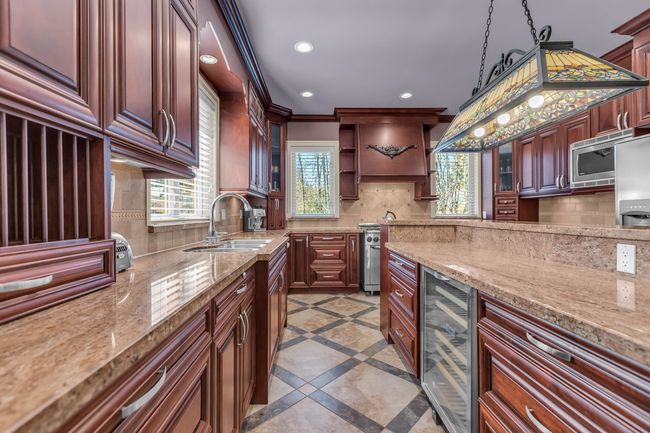 Kitchen with a sink, wine cooler, backsplash, recessed lighting, and inlaid floor details | Image 13