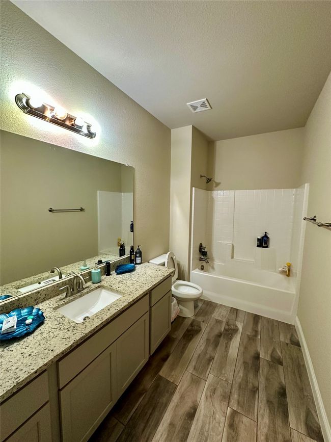 Full bathroom with wood finished floors, vanity, tub / shower combination, and a textured ceiling | Image 20