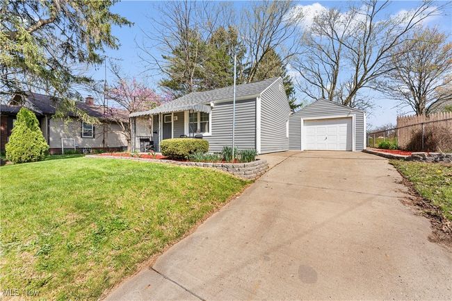 Ranch-style house with a front yard, an outdoor structure, a detached garage, concrete driveway, and fence | Image 11