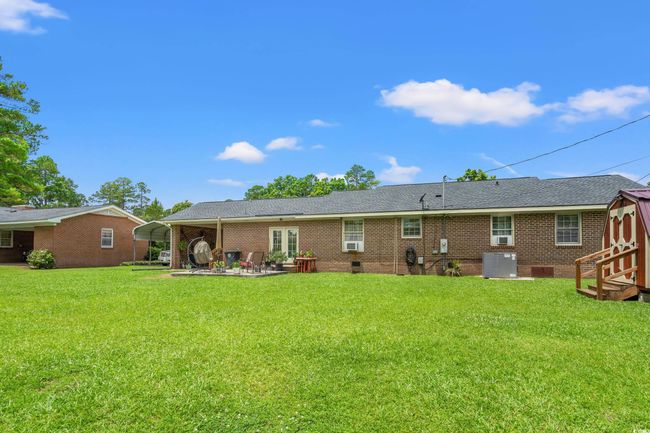 Rear view of property featuring a lawn, a storage unit, a detached carport, and brick siding | Image 16