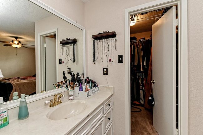 Bathroom with vanity, a spacious closet, a textured wall, a textured ceiling, and a ceiling fan | Image 16